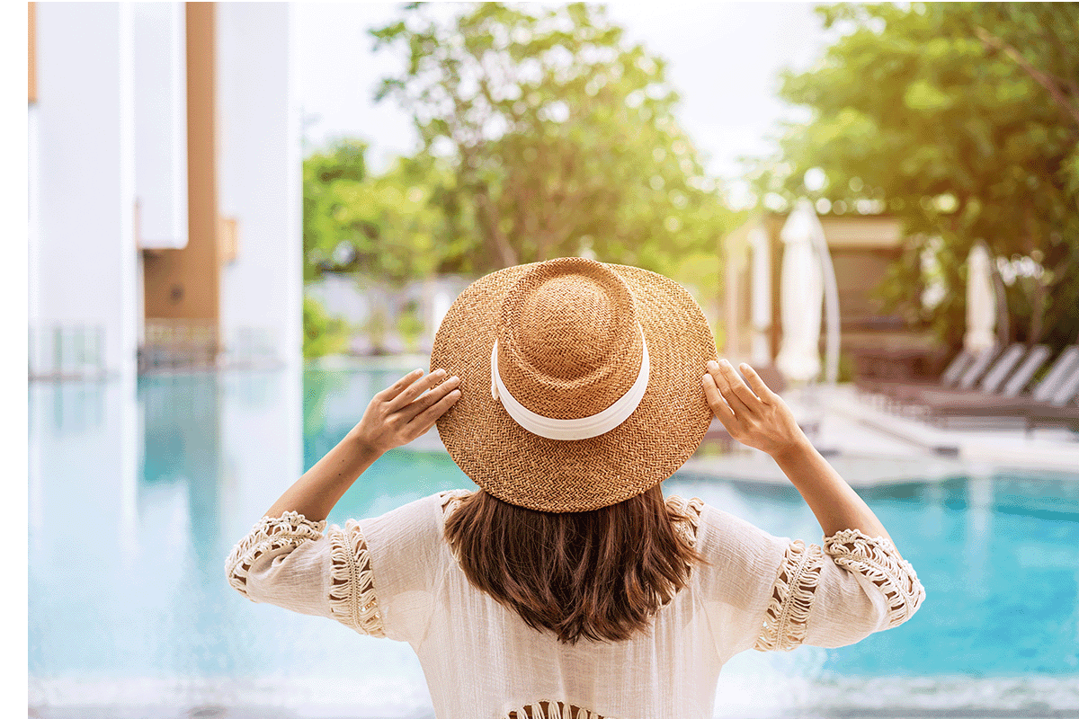 Woman wearing a sunhat standing in front of a pool
