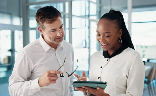 Two colleagues reviewing documents on a tablet, highlighting targeted advertising for professional services.