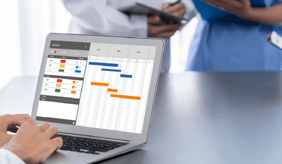 Close-up of a healthcare worker using a laptop with scheduling and performance data on screen, symbolizing tools that support streamlined healthcare marketing operations.