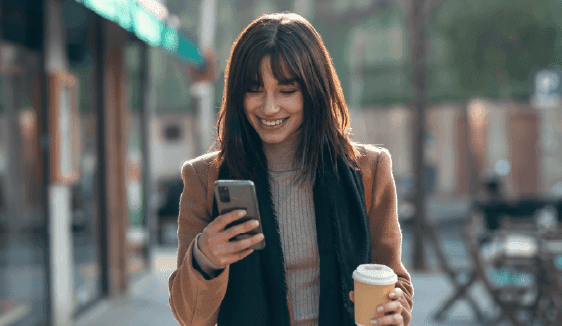 Woman checking her phone while walking, representing on-the-go engagement with programmatic display ads.