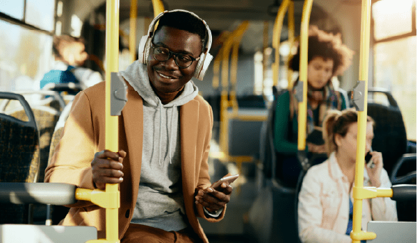 Person wearing headphones and using a smartphone while riding public transit, representing streaming audio and podcast listeners reachable through programmatic audio advertising.