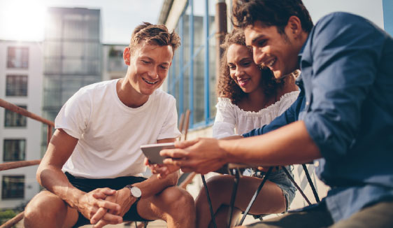 Friends watching a video on a smartphone and laptop, illustrating how programmatic video ads reach viewers across mobile devices.